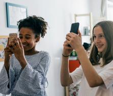 two teens taking photos with smartphones