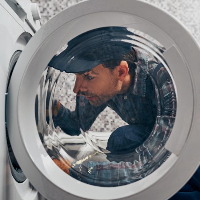 repair man looking in dryer